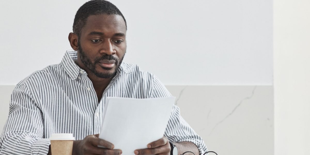 A person intently studying papers, reflecting the careful scrutiny needed to understand AI detector limitations and where they struggle.
