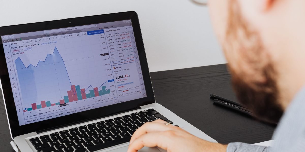 A business leader intently analyzes financial data on multiple screens, emphasizing ongoing monitoring and risk management.