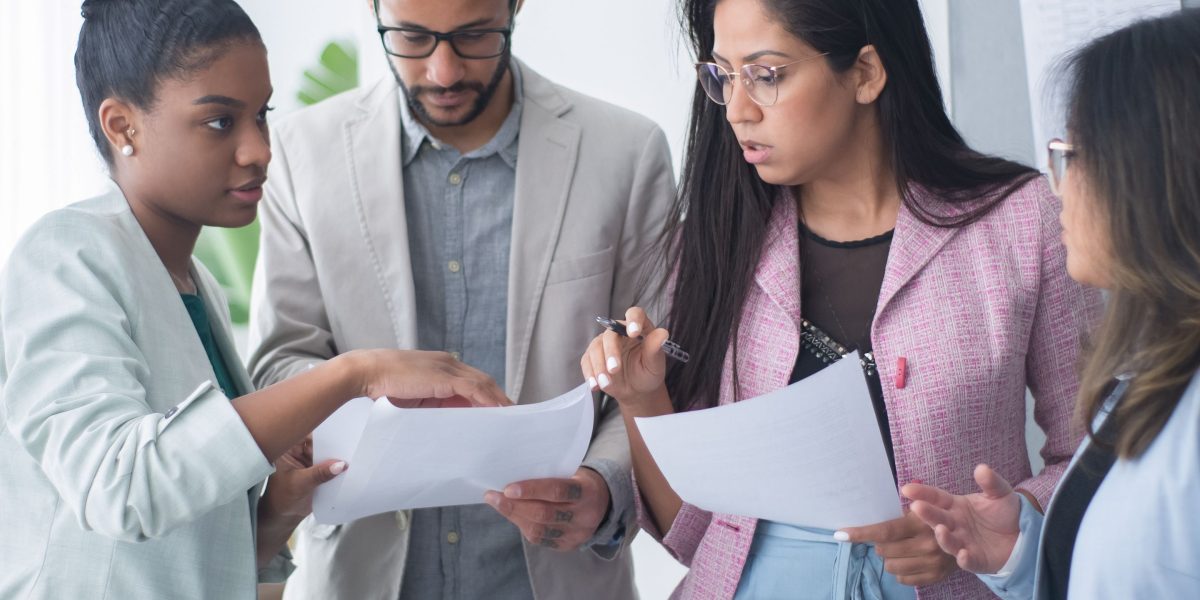 A diverse team collaborating and strategizing to overcome complex technical challenges in a dynamic work environment.