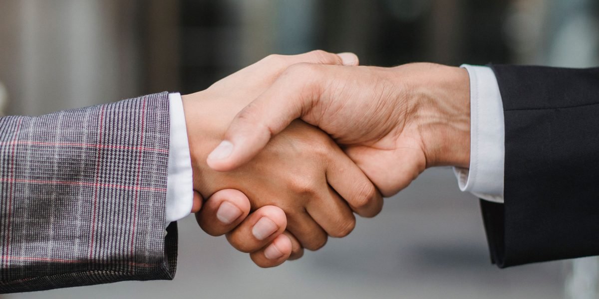 A handshake symbolizing the collaboration between academic research and industry for AI commercialization.